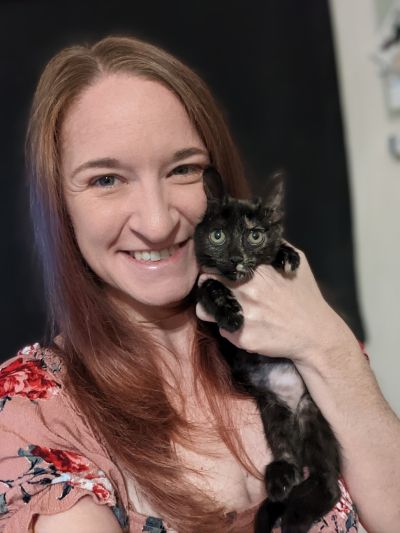 Brunette white woman holding a tortoiseshell kitten